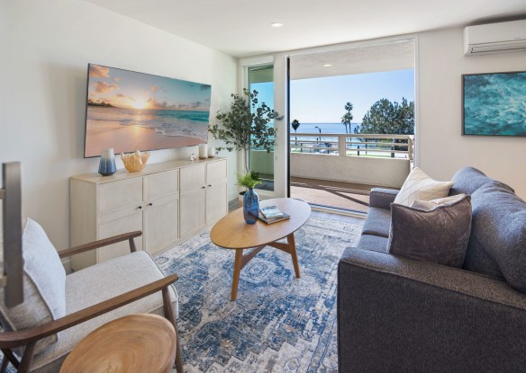 View of the living room with a balcony and an ocean vista