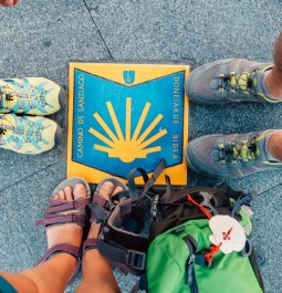 pilgrims standing around a camino marker on the sidewalk