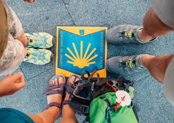 pilgrims standing around a camino marker on the sidewalk