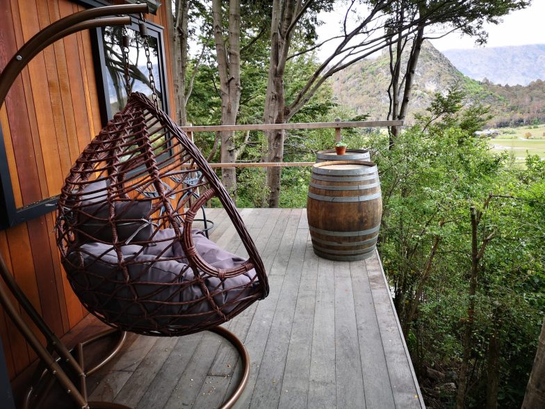 Egg-shaped wooden chair on balcony of treehouse