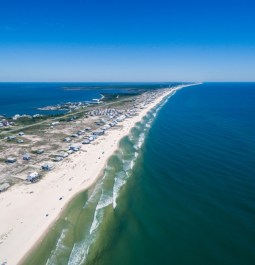 aerial view of beach peninsula under blue skies