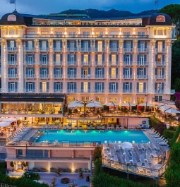 Exterior of a historic hotel with a swimming pool in the evening