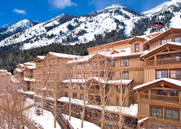 Mountainside log cabin-style hotel with mountain peaks in background